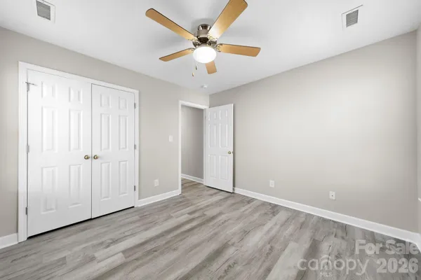an empty room with wooden floor and ceiling fan