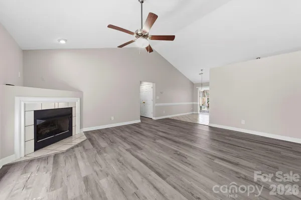 an empty room with wooden floor a ceiling fan a fireplace