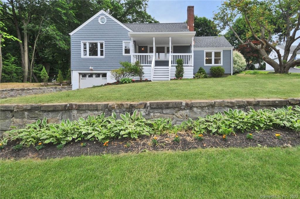 a front view of a house with a garden and trees