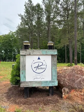 a view of a sign in a park with large trees