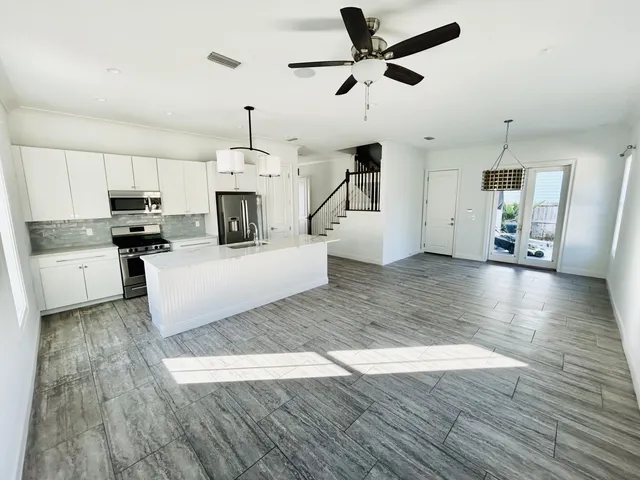 a kitchen with stainless steel appliances a stove a refrigerator a center island a stove and white cabinets