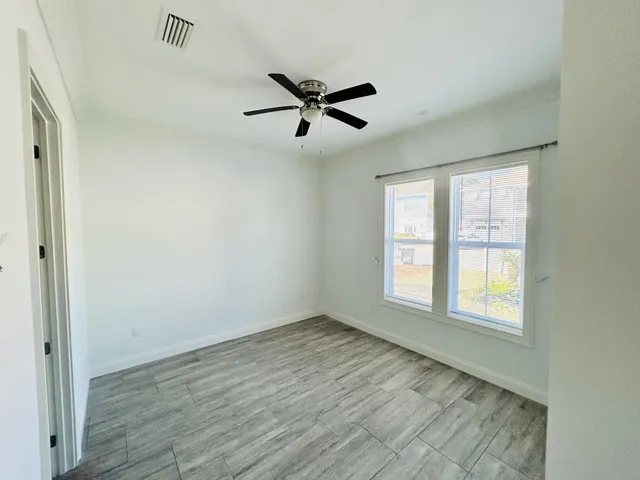 a view of empty room with wooden floor and fan