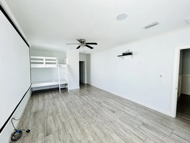 an empty room with wooden floor ceiling fan and windows