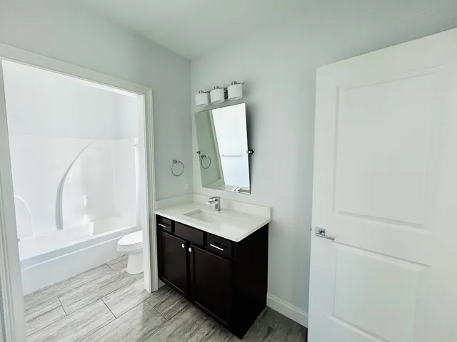 a bathroom with a double vanity sink toilet mirror and bathtub