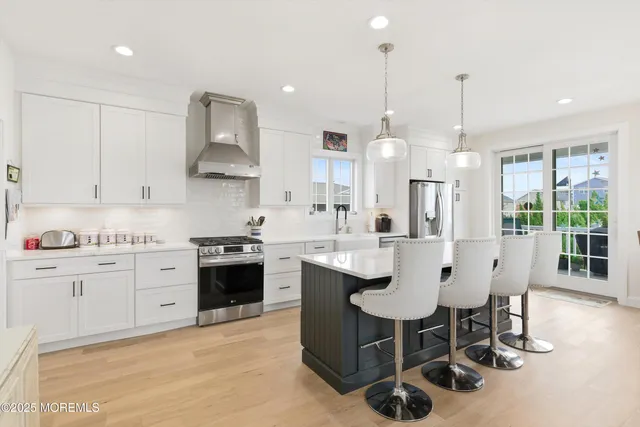 a kitchen with stainless steel appliances granite countertop a sink a stove a refrigerator and island with wooden floor