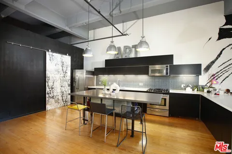 a kitchen with stainless steel appliances granite countertop a sink a stove and a wooden floors