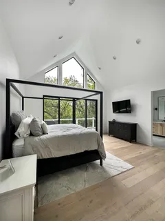 a bedroom with bed and large windows
