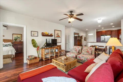 a living room with furniture kitchen view and a wooden floor