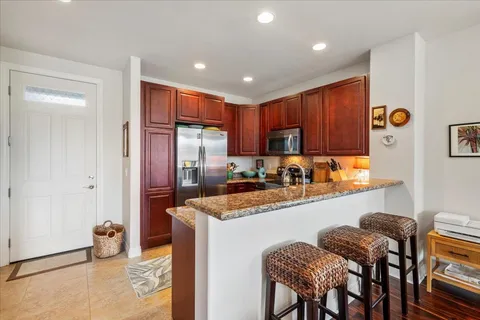 a kitchen with stainless steel appliances granite countertop a refrigerator a sink a stove and island