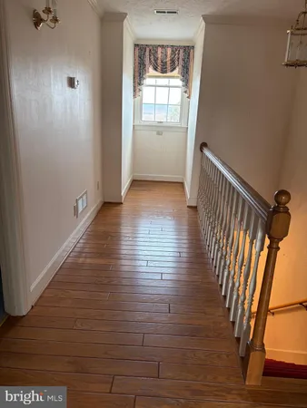 a view of a hallway with wooden floor and stairs