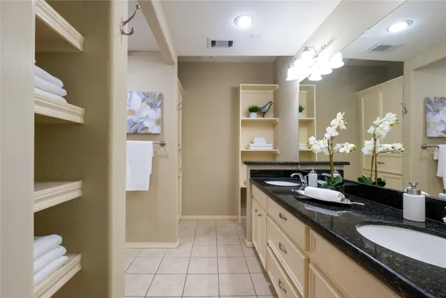 a spacious bathroom with a granite countertop double vanity sink a mirror and a shower