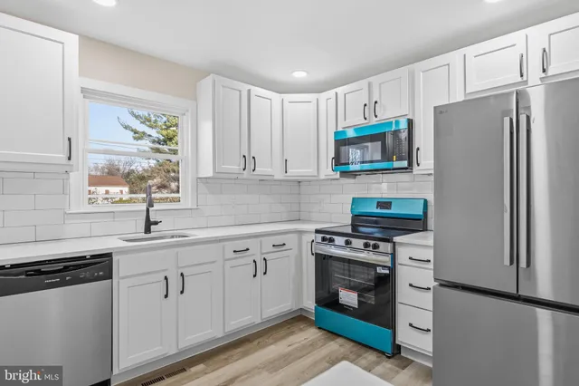 a kitchen with white cabinets white stainless steel appliances and sink