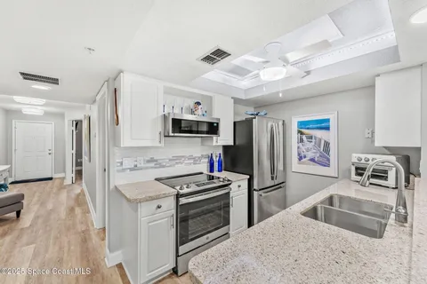 a kitchen with granite countertop a refrigerator stove and sink