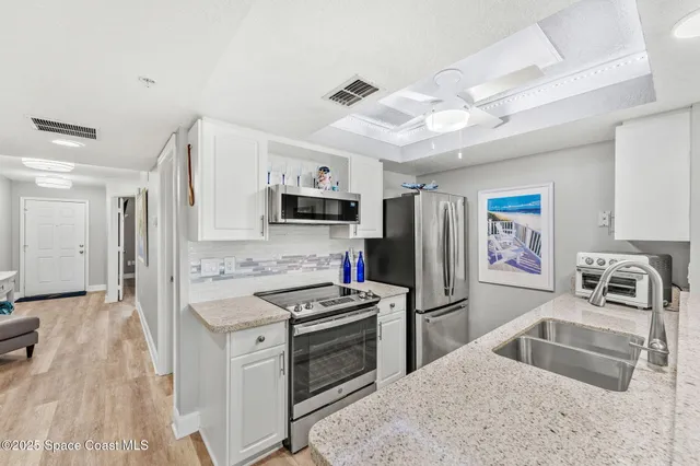 a kitchen with granite countertop a refrigerator stove and sink