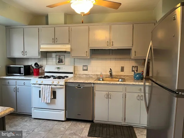 a kitchen with stainless steel appliances granite countertop a sink a stove and refrigerator