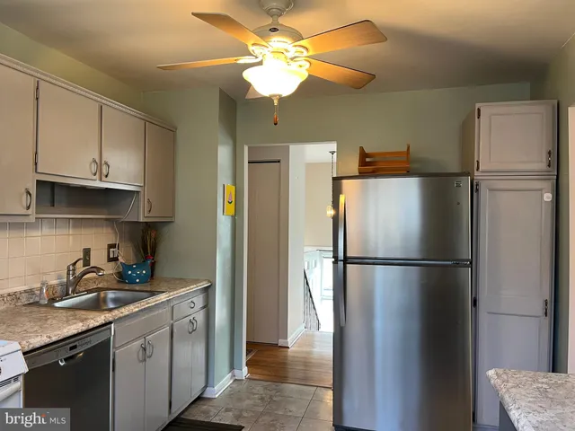 a kitchen with stainless steel appliances granite countertop a refrigerator a sink a stove and white cabinets