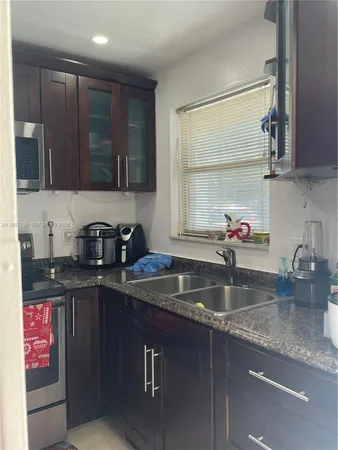 a kitchen with kitchen island granite countertop a sink stainless steel appliances and cabinets