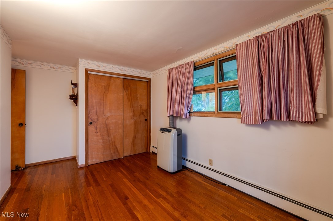 1950 Rush Road Wickliffe, OH 44092 - Photo 15 of 50 Unfurnished bedroom featuring a baseboard radiator, wood finished floors, and a closet