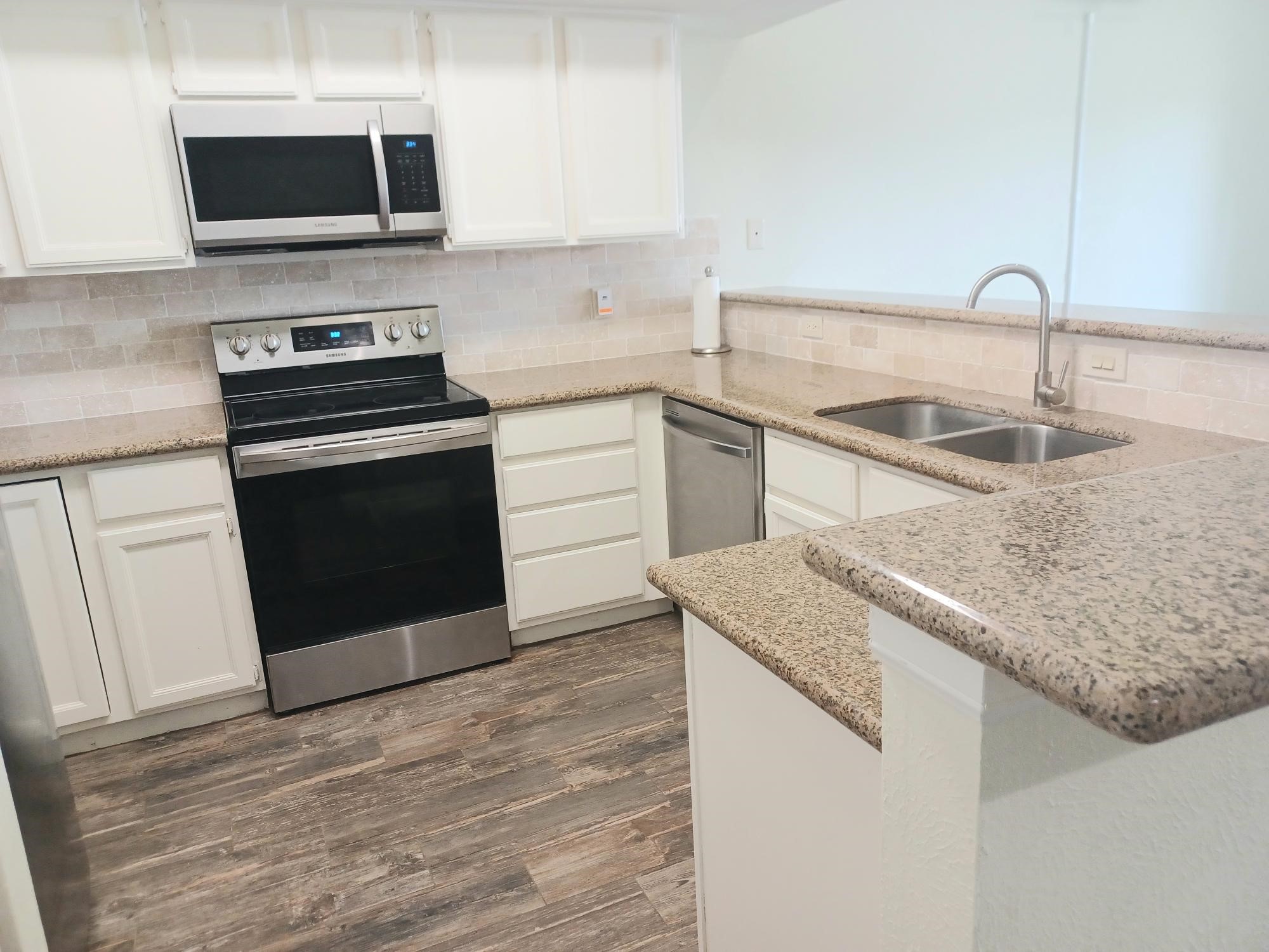 128 April Point Drive South Conroe, TX 77356 - Photo 7 of 26 a kitchen with granite countertop a sink and a stove top oven with wooden floor