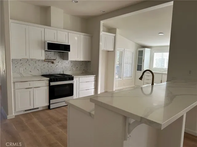 a kitchen with granite countertop a stove top oven a sink and dishwasher with wooden floor