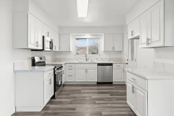 a kitchen with stainless steel appliances granite countertop a sink and cabinets with wooden floors