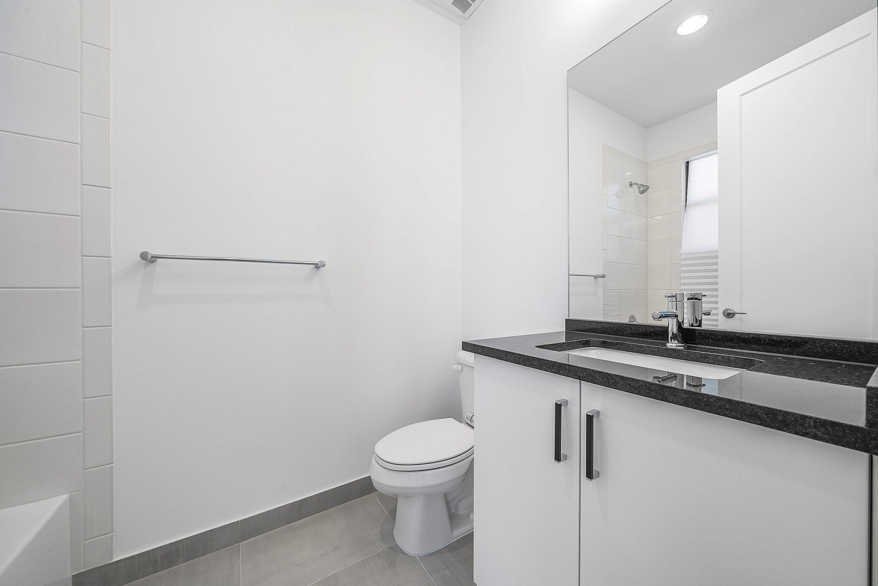 8260 Royal County Down Road Boca Raton, FL 33434 - Photo 42 of 115 a bathroom with a granite countertop sink a toilet and a mirror