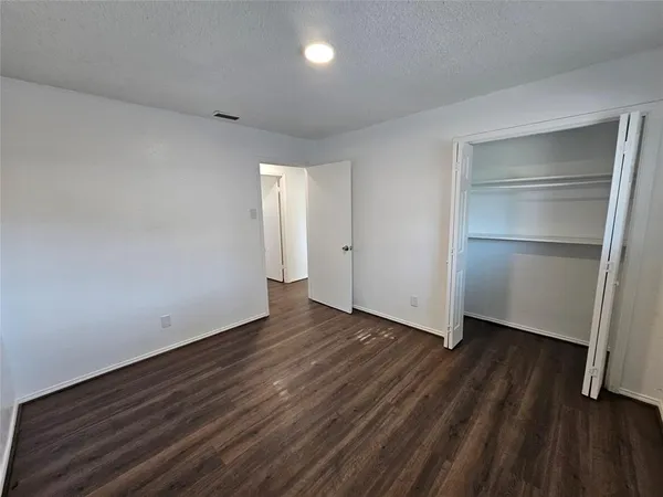 a view of an empty room with wooden floor & closet