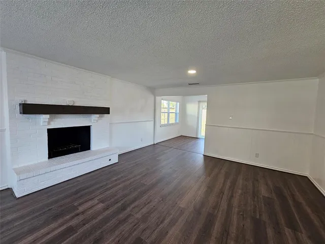 a view of an empty room and a fireplace with wooden floor