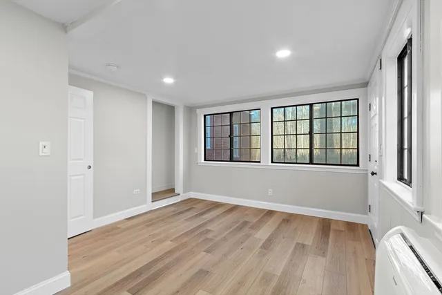 a view of an empty room with a window and wooden floor