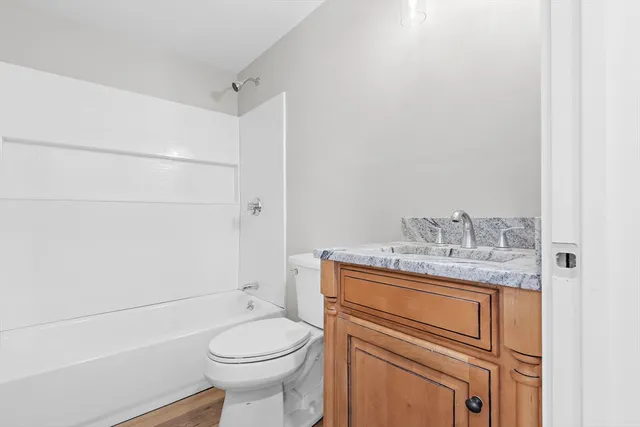 a bathroom with a granite countertop toilet sink and mirror