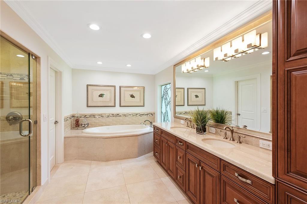809 Buttonbush Lane Naples, FL 34108 - Photo 14 of 23 a spacious bathroom with a double vanity sink a large mirror and a bathtub