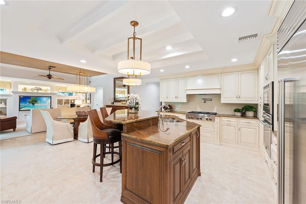 809 Buttonbush Lane Naples, FL 34108 - Photo 6 of 23 a open kitchen with stainless steel appliances granite countertop a stove top oven a sink dishwasher a dining table and chairs with wooden floor