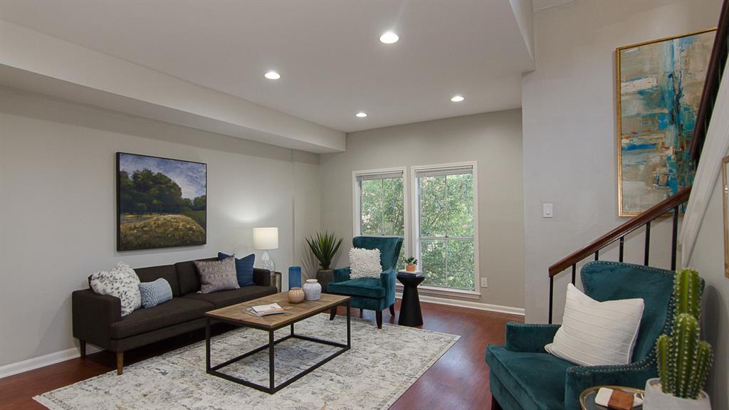 Warm wood flooring and recessed lighting illuminate this welcoming living space.