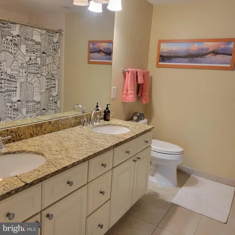 a bathroom with a granite countertop sink a toilet and a mirror