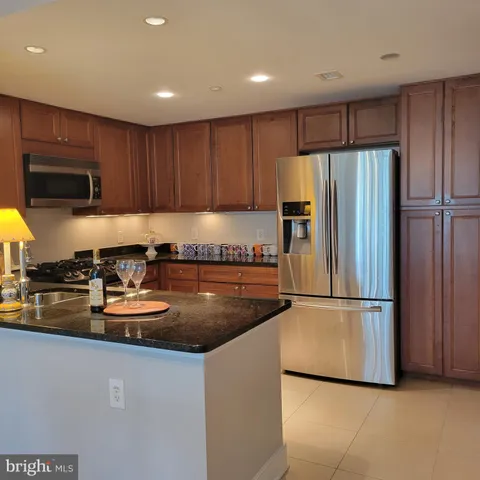 a kitchen with granite countertop a refrigerator and a sink