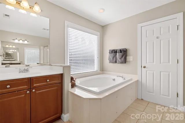 a spacious bathroom with a tub sink and mirror