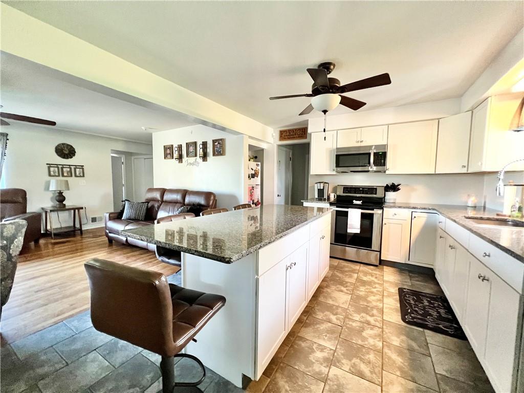 2175 Frew Mill Road New Castle, PA 16101 - Photo 12 of 25 a large white kitchen with kitchen island a living room a couch and a ceiling fan