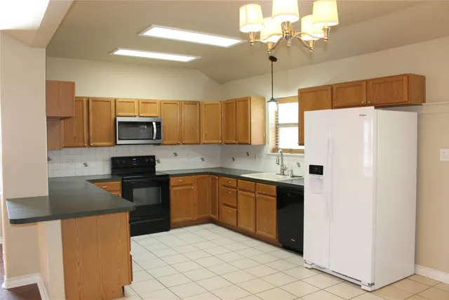 a kitchen with granite countertop cabinets a refrigerator a sink dishwasher and a stove