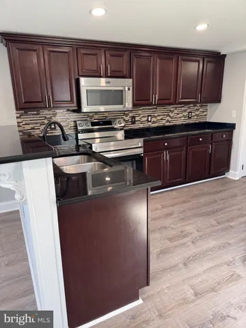 a kitchen with stainless steel appliances granite countertop a stove a sink and a microwave