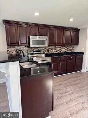 a kitchen with stainless steel appliances granite countertop a stove top oven a sink and dishwasher a refrigerator with wooden floor