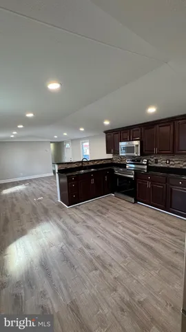 a large kitchen with kitchen island granite countertop a stove top oven a sink and a dishwasher with wooden floor