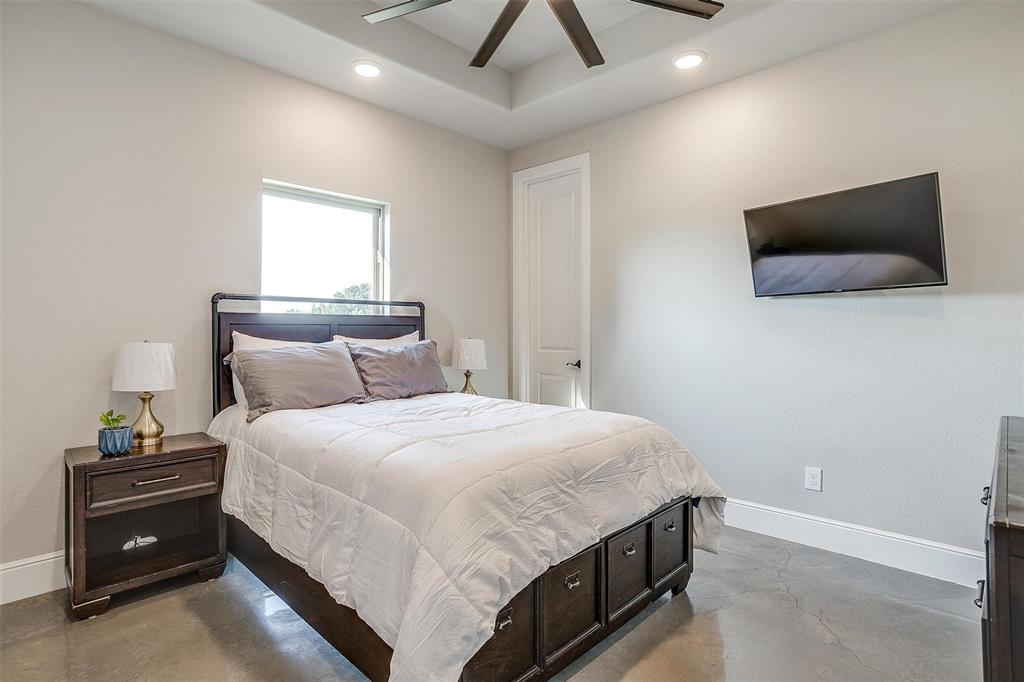 3207 Hummingbird Court Granbury, TX 76049 - Photo 23 of 40 a bedroom with a bed and a flat tv screen on a dresser