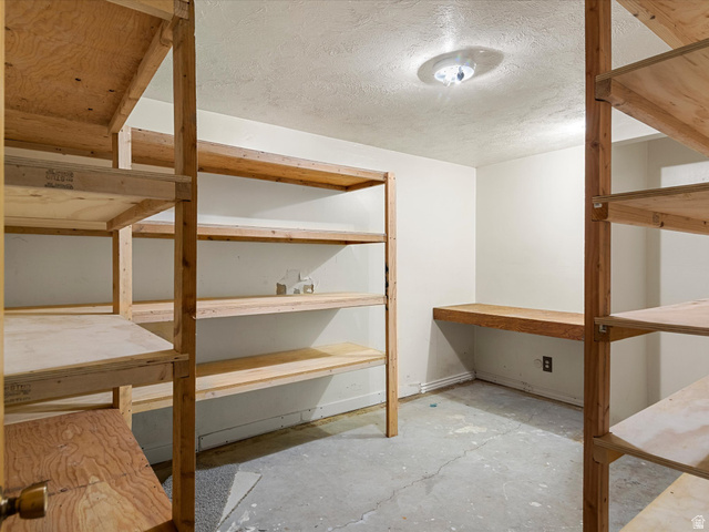 15680 North Beaver Dam Road Collinston, UT 84306 - Photo 36 of 49 Storage room with built-in wood shelving, an integrated wood-finish workstation, and a flush-mount ceiling light