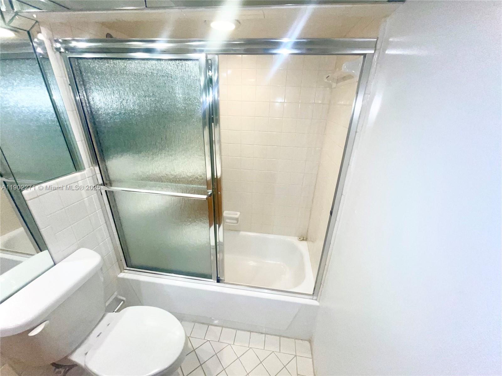 2175 Northeast 56th Street, Unit 105 Fort Lauderdale, FL 33308 - Photo 20 of 26 a bathroom with a glass shower door and a mirror