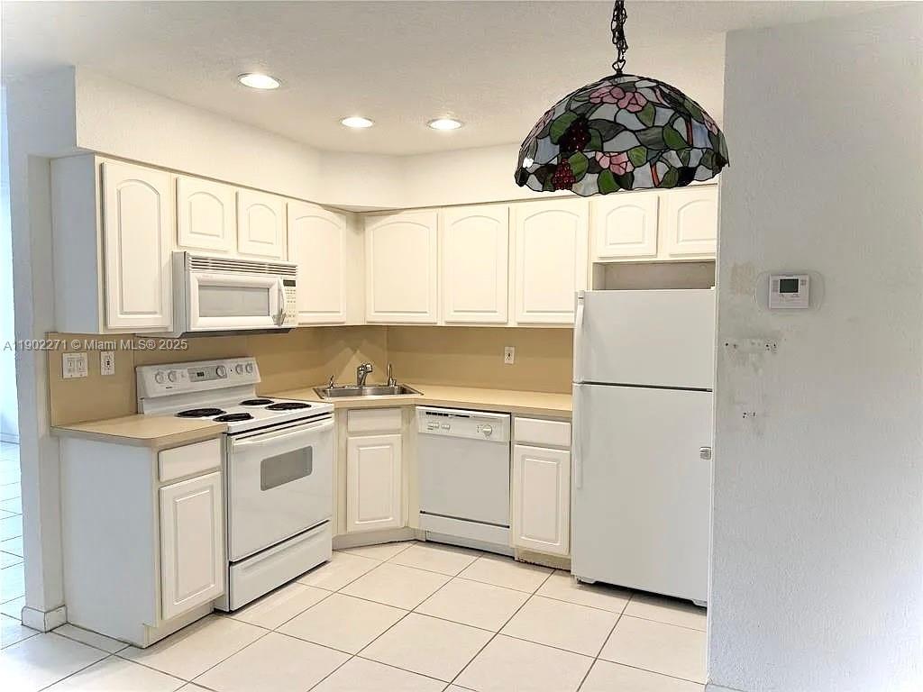 2175 Northeast 56th Street, Unit 105 Fort Lauderdale, FL 33308 - Photo 21 of 26 a kitchen with a white cabinets and white appliances
