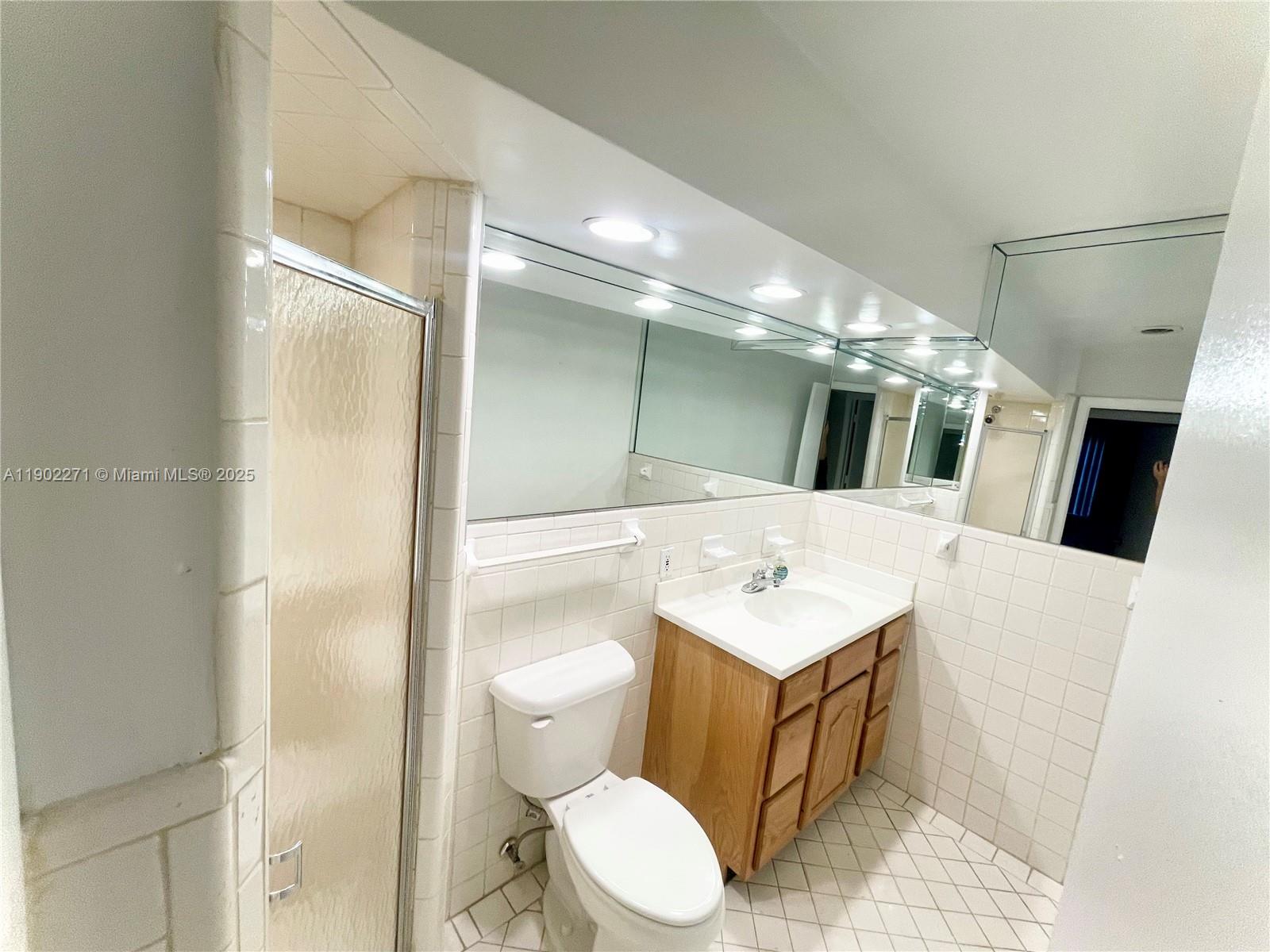 2175 Northeast 56th Street, Unit 105 Fort Lauderdale, FL 33308 - Photo 9 of 26 a bathroom with a toilet sink and mirror
