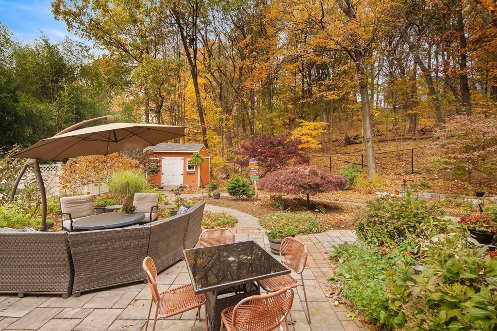 447 Waban Avenue Newton, MA 02462 - Photo 37 of 42 a view of a patio with couches table and chairs under an umbrella with large trees