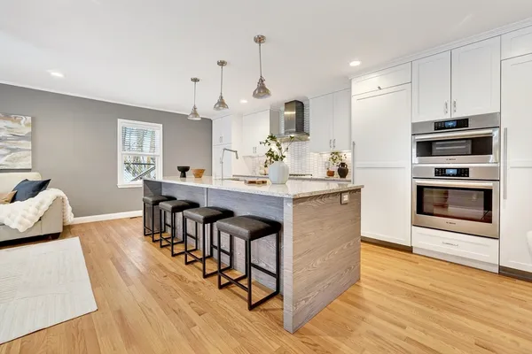 a kitchen with stainless steel appliances kitchen island granite countertop a table chairs stove and white cabinets