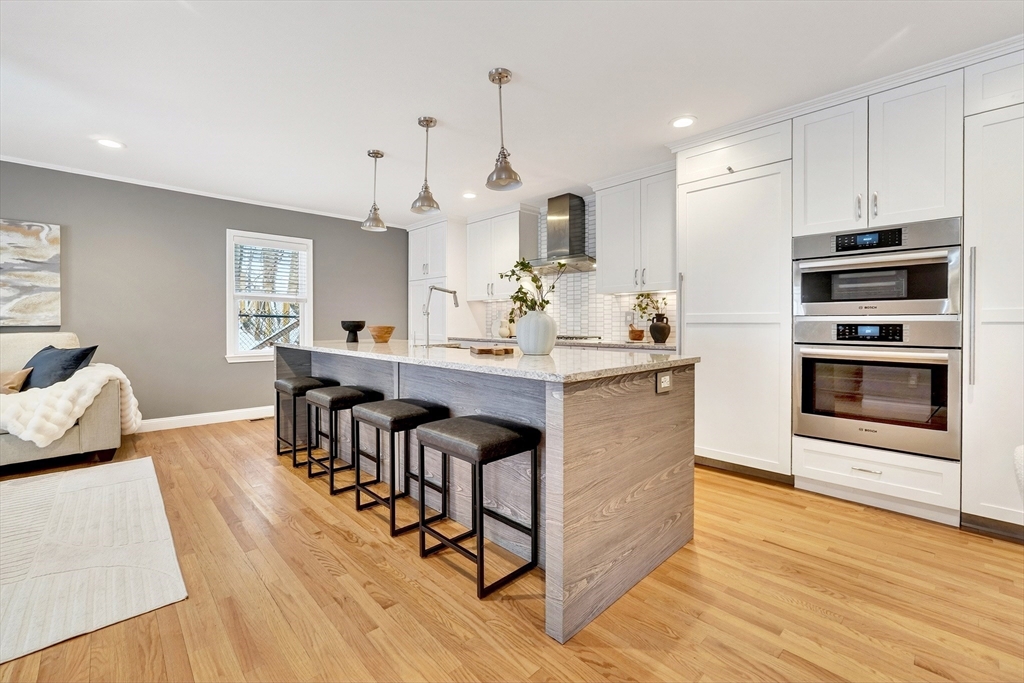 447 Waban Avenue Newton, MA 02462 - Photo 5 of 42 a kitchen with stainless steel appliances kitchen island granite countertop a table chairs stove and white cabinets
