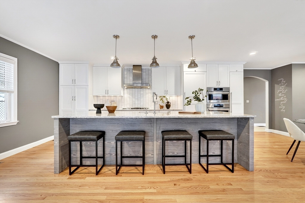 447 Waban Avenue Newton, MA 02462 - Photo 6 of 42 a kitchen with stainless steel appliances granite countertop a sink a stove a dining table and chairs with wooden floor